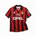 Fronte maglia Milan 1995/96 con strisce rosse e nere, colletto a polo e Scudetto.
