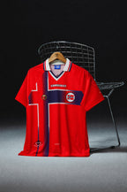 Norvegia Maglia Home 1997/98 World Cup appesa in esposizione con dettagli storici della divisa.
